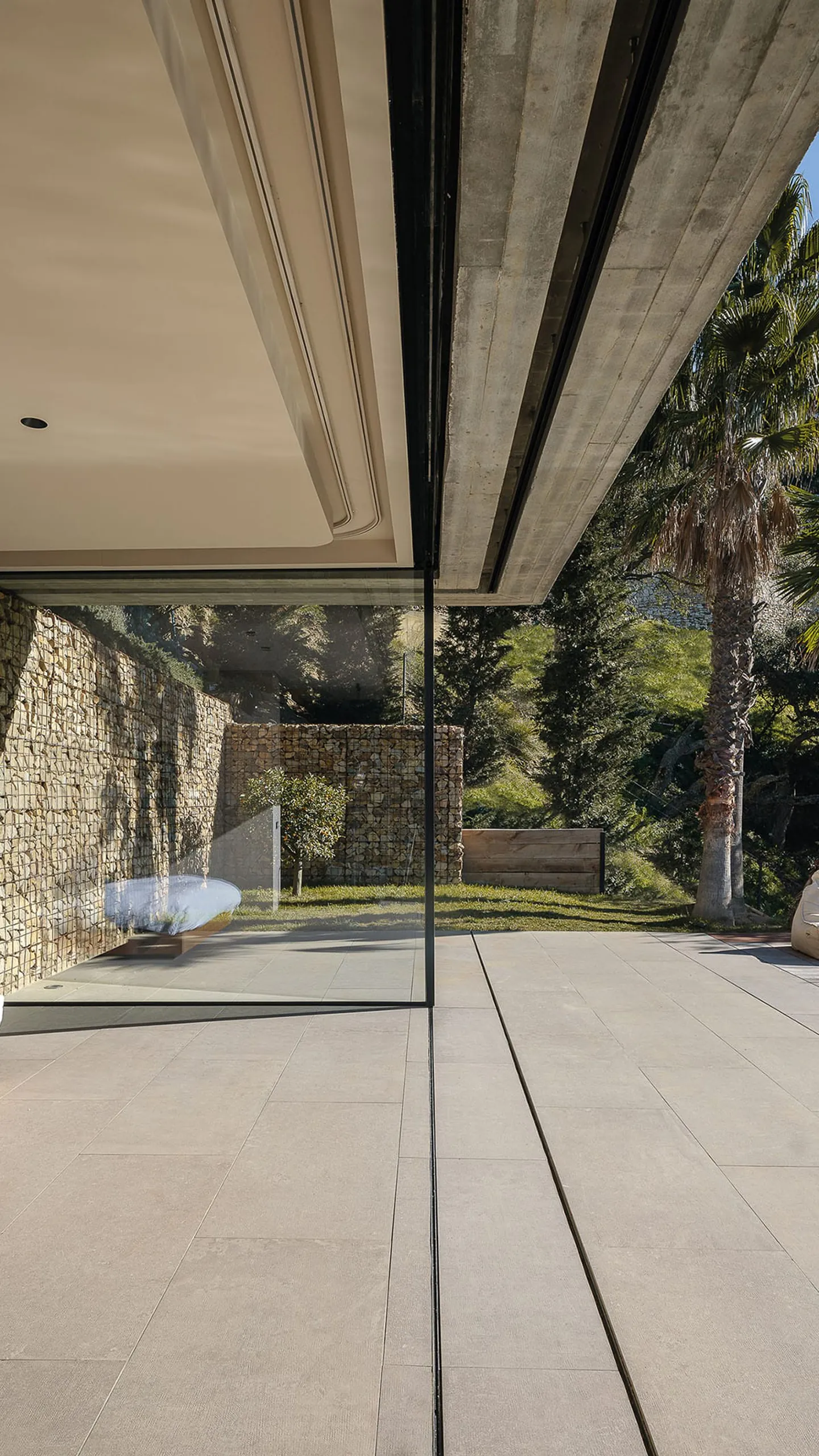 Large sliding glass wall opening toward a Mediterranean garden